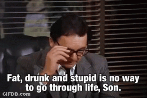 A Man In A Suit And Tie Is Sitting In A Chair With His Eyes Closed And Glasses On . GIF