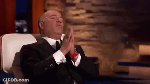 A Man In A Suit And Tie Is Sitting In A Chair With His Eyes Closed And His Hands Folded In Prayer . GIF