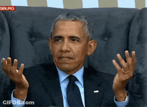 A Man In A Suit And Tie Is Sitting In A Chair With His Hands In The Air GIF