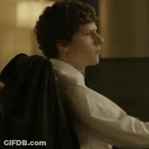 A Man In A Suit And Tie Is Sitting In A Chair With His Jacket On His Back . GIF