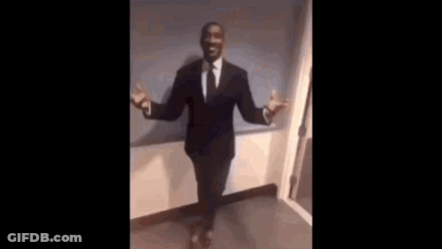 A Man In A Suit And Tie Is Sitting In A Chair With His Legs Crossed . GIF