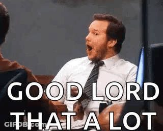 A Man In A Suit And Tie Is Sitting In A Chair With His Mouth Open And Says `` Good Lord That A Lot '' GIF