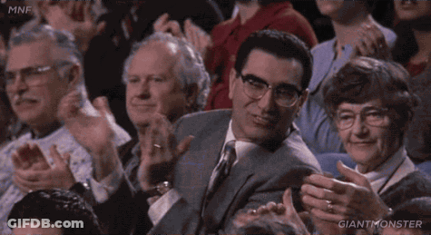 A Man In A Suit And Tie Is Sitting In A Crowd Clapping And Says That 'S My Dog . GIF