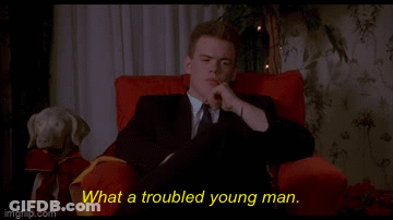 A Man In A Suit And Tie Is Sitting In A Red Chair With The Words What A Troubled Young Man Behind Him GIF