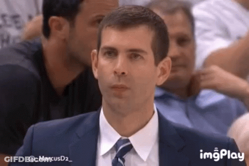 A Man In A Suit And Tie Is Sitting In A Stadium . GIF