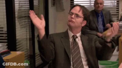 A Man In A Suit And Tie Is Sitting In An Office With His Hands Up . GIF