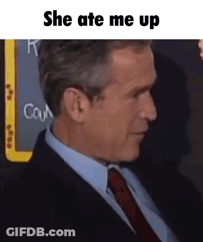 A Man In A Suit And Tie Is Sitting In Front Of A Blackboard That Says She Ate Me Up . GIF