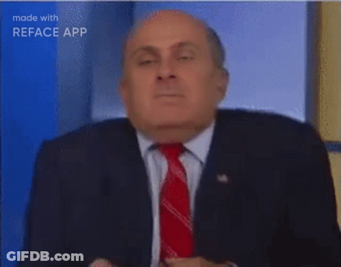 A Man In A Suit And Tie Is Sitting In Front Of A Blue Background . GIF