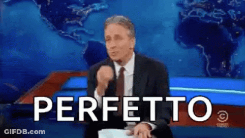 A Man In A Suit And Tie Is Sitting In Front Of A Blue Background With The Word Perfetto Written In White Letters . GIF