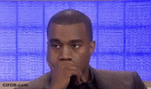 A Man In A Suit And Tie Is Sitting In Front Of A Blue Wall . GIF