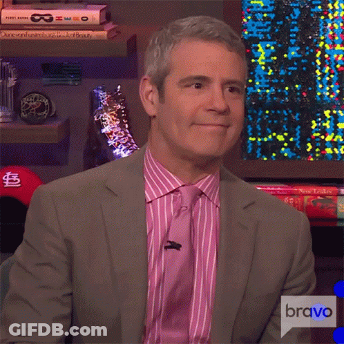 A Man In A Suit And Tie Is Sitting In Front Of A Bravo Logo GIF