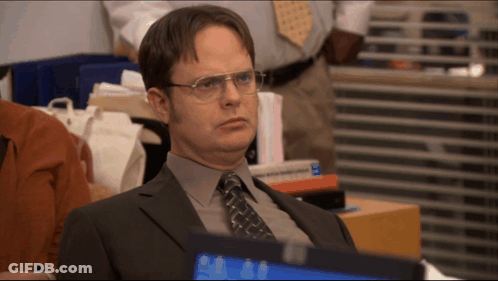 A Man In A Suit And Tie Is Sitting In Front Of A Computer GIF