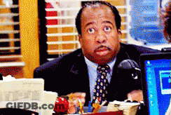 A Man In A Suit And Tie Is Sitting In Front Of A Computer Monitor GIF
