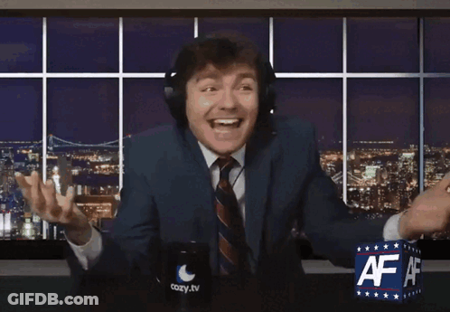 A Man In A Suit And Tie Is Sitting In Front Of A Cozy Tv Sign GIF