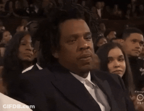 A Man In A Suit And Tie Is Sitting In Front Of A Crowd And A Sign That Says Rep On It GIF