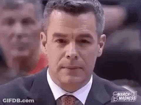 A Man In A Suit And Tie Is Sitting In Front Of A Crowd Of People . GIF