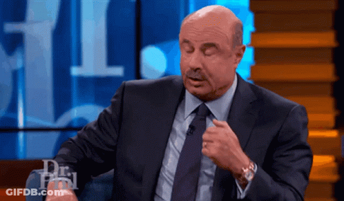 A Man In A Suit And Tie Is Sitting In Front Of A Dr Phil Sign GIF
