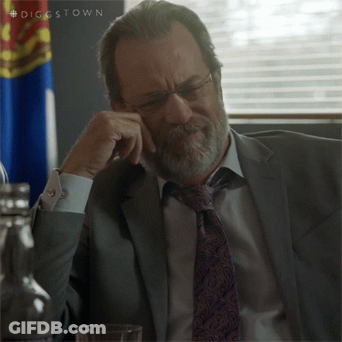 A Man In A Suit And Tie Is Sitting In Front Of A Flag With The Hashtag Diggstown GIF