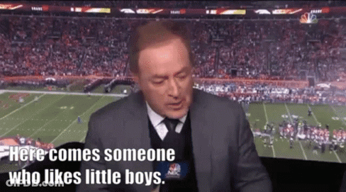 A Man In A Suit And Tie Is Sitting In Front Of A Football Field Talking Into A Microphone . GIF