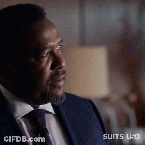 A Man In A Suit And Tie Is Sitting In Front Of A Lamp With The Words Suits Usa On The Bottom Right GIF