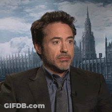 A Man In A Suit And Tie Is Sitting In Front Of A Large Building GIF