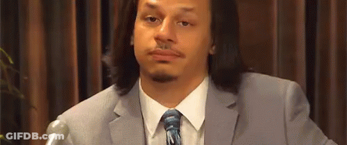 A Man In A Suit And Tie Is Sitting In Front Of A Microphone And Making A Funny Face . GIF