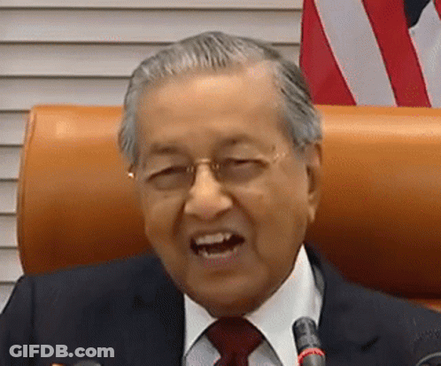 A Man In A Suit And Tie Is Sitting In Front Of A Microphone And Smiling . GIF