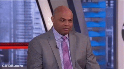 A Man In A Suit And Tie Is Sitting In Front Of A Microphone In A Studio . GIF