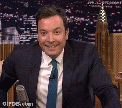 A Man In A Suit And Tie Is Sitting In Front Of A Microphone . GIF