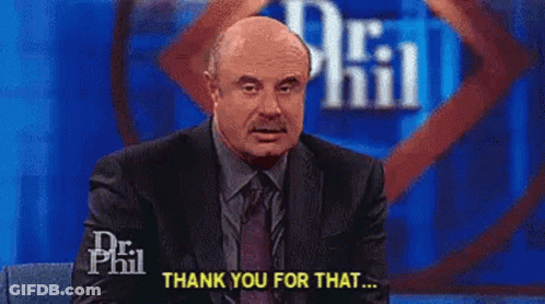 A Man In A Suit And Tie Is Sitting In Front Of A Microphone On A Stage And Saying `` Thank You For That '' . GIF