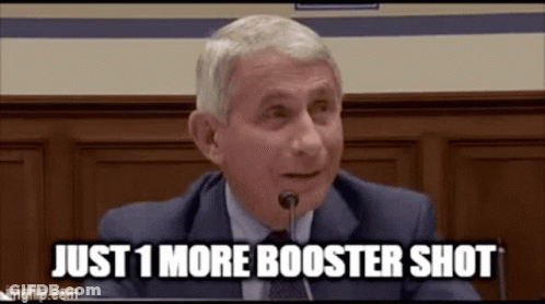 A Man In A Suit And Tie Is Sitting In Front Of A Microphone . GIF