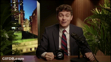 A Man In A Suit And Tie Is Sitting In Front Of A Microphone With A Mug That Says Af GIF
