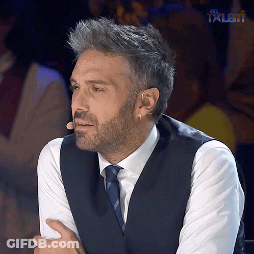 A Man In A Suit And Tie Is Sitting In Front Of A Microphone With The Word Talent Above Him GIF