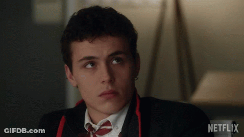 A Man In A Suit And Tie Is Sitting In Front Of A Netflix Sign GIF