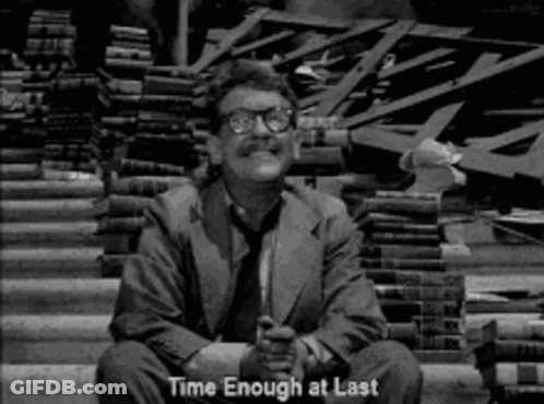 A Man In A Suit And Tie Is Sitting In Front Of A Pile Of Books And Says `` Time Enough At Last '' . GIF