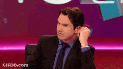 A Man In A Suit And Tie Is Sitting In Front Of A Purple Screen . GIF