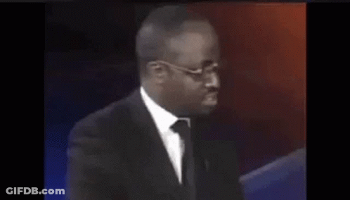 A Man In A Suit And Tie Is Sitting In Front Of A Red And Blue Background . GIF