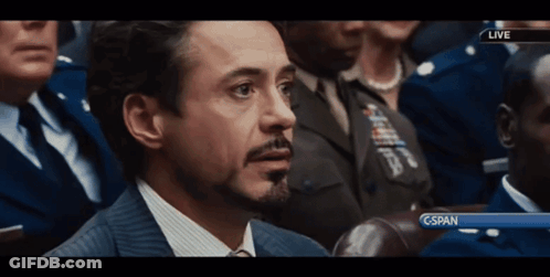 A Man In A Suit And Tie Is Sitting In Front Of A Screen That Says Cspan GIF