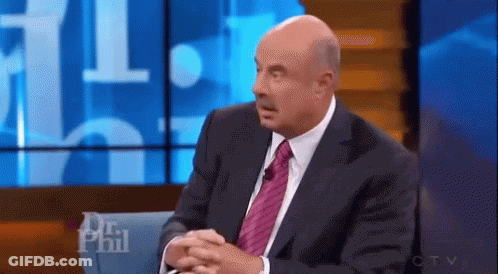 A Man In A Suit And Tie Is Sitting In Front Of A Screen That Says Dr Phil On It . GIF