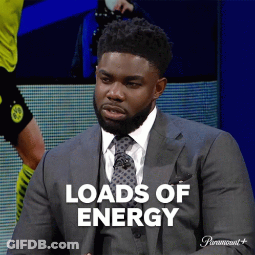 A Man In A Suit And Tie Is Sitting In Front Of A Screen That Says Loads Of Energy GIF