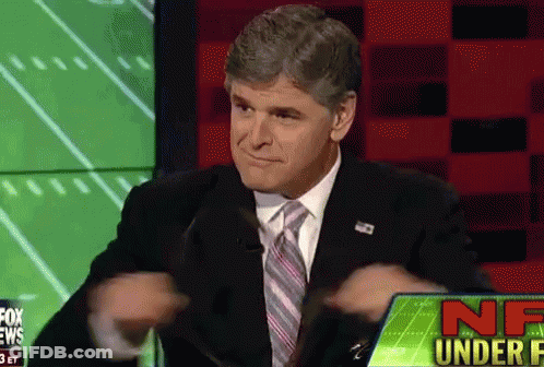 A Man In A Suit And Tie Is Sitting In Front Of A Screen That Says Nf Under F GIF