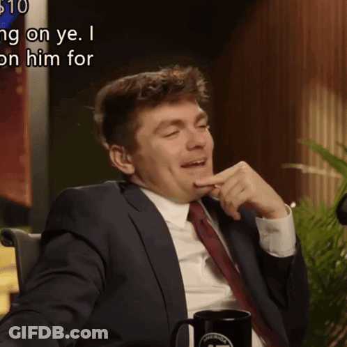 A Man In A Suit And Tie Is Sitting In Front Of A Sign That Says ' $ 10 ' On It GIF