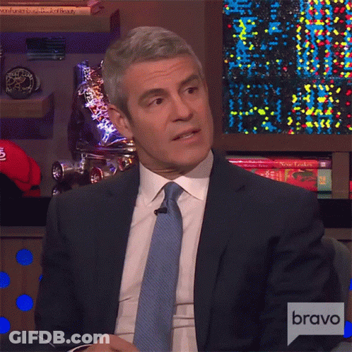 Man In Suit Sitting In Front Of Bravo Sign GIF