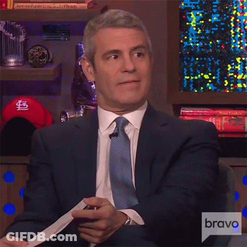 Man In Suit Sitting In Front Of Bravo Sign GIF