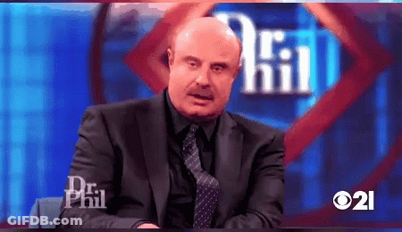 A Man In A Suit And Tie Is Sitting In Front Of A Sign That Says Dr Phil GIF