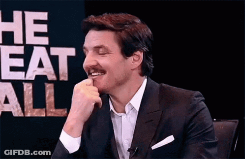 A Man In A Suit And Tie Is Sitting In Front Of A Sign That Says `` He Eats All '' And Smiling . GIF