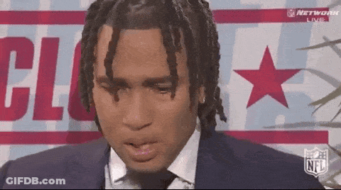 A Man In A Suit And Tie Is Sitting In Front Of A Sign That Says Nfl GIF