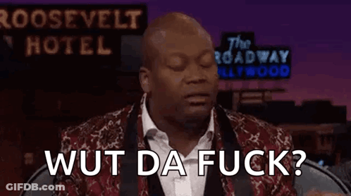 A Man In A Suit And Tie Is Sitting In Front Of A Sign That Says The Roosevelt Hotel . GIF