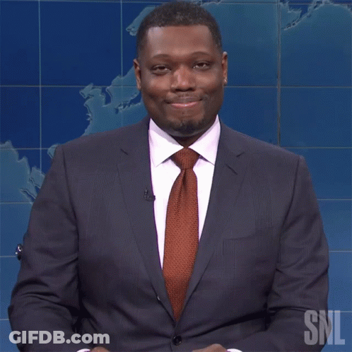 A Man In A Suit And Tie Is Sitting In Front Of A Snl Logo GIF