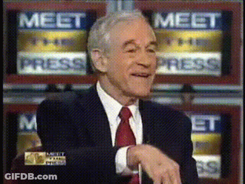 A Man In A Suit And Tie Is Sitting In Front Of A Wall That Says Meet Press GIF